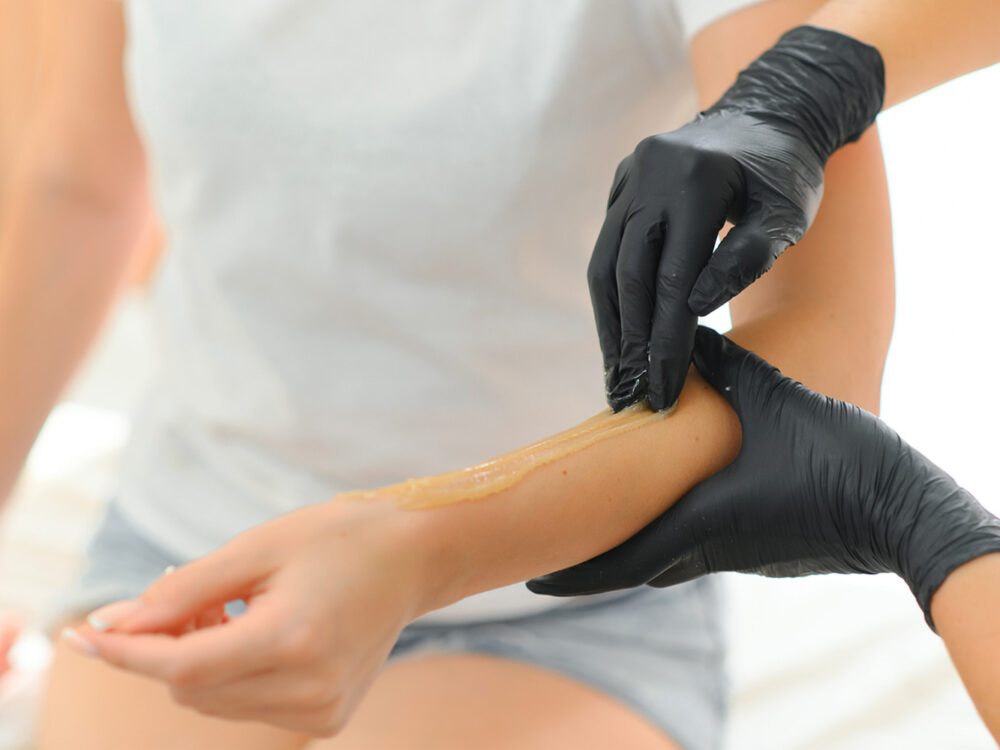 Sugar paste hair removal procedure - shugaring. Cosmetologist applies sugar paste to the hand.